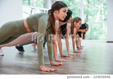 Doing plank. Group of women practicing fitness in the gym 124630846