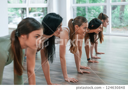 Doing plank. Group of women practicing fitness in the gym 124630848