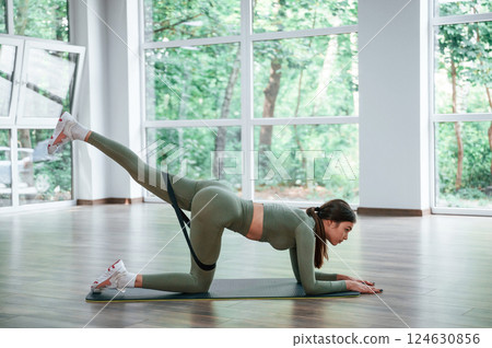 Side view. Legs exercise. Woman in sportive clothes is having fitness day in the gym Side view. Legs exercise. Woman in sportive clothes is having fitness day in the gym 124630856