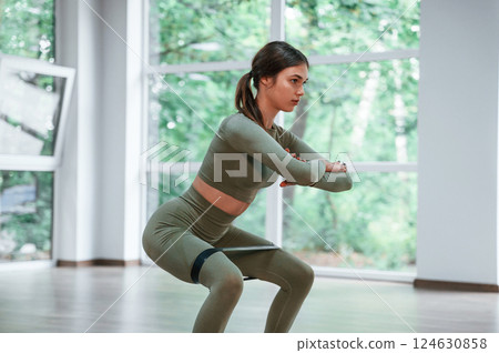 Doing squats. Woman in sportive clothes is having fitness day in the gym 124630858