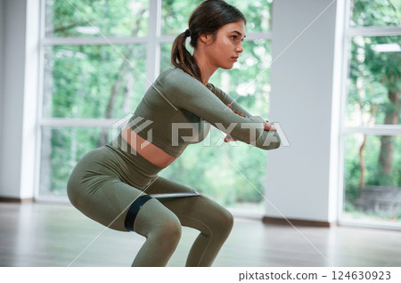 Doing squats. Woman in sportive clothes is having fitness day in the gym 124630923