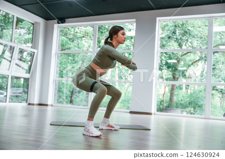 Doing squats. Woman in sportive clothes is having fitness day in the gym 124630924