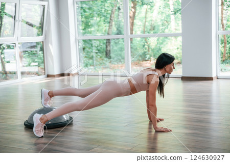 Using special platform. Woman in sportive clothes is having fitness day in the gym Using special platform. Woman in sportive clothes is having fitness day in the gym 124630927