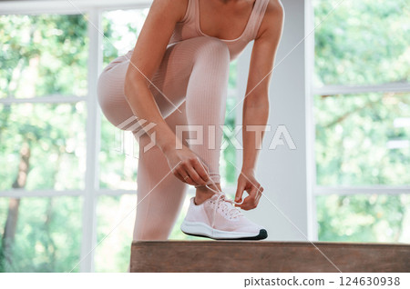Ties shoelaces. Woman in sportive clothes is having fitness day in the gym 124630938