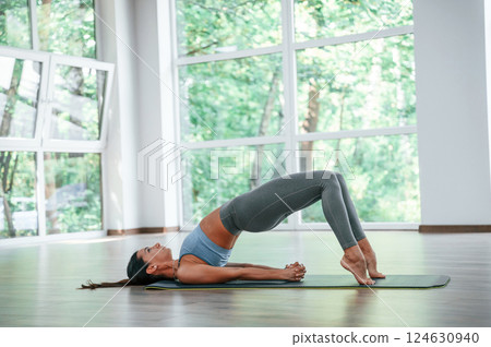 Against big window. Woman in sportive clothes is having fitness day in the gym Against big window. Woman in sportive clothes is having fitness day in the gym 124630940