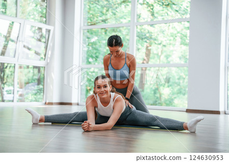Stretching the legs. Female trainer helping woman with exercises in the gym 124630953