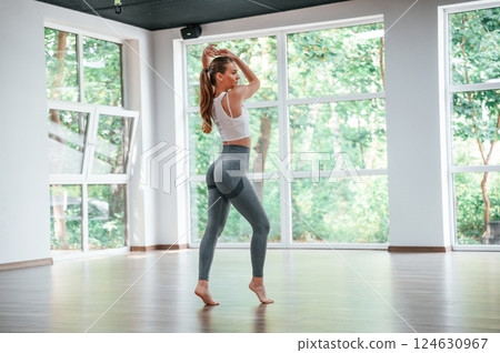 Standing and posing for a camera. Woman in sportive clothes is having fitness day in the gym 124630967