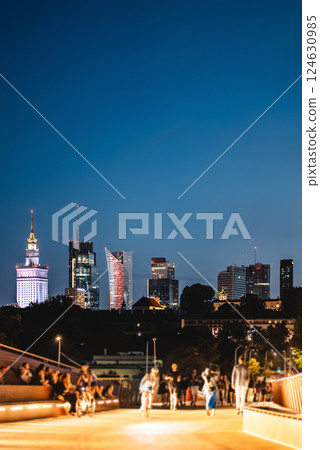 night over skyline of Warsaw city with skyscrapers and downtown district, crowd of people walking, tourist travel destination, rush hour in capital of Poland 124630985