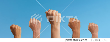 Clenched fists raised in unity, symbolizing freedom and feminist power. Women and girls in a crowd, 124631180
