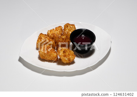 Crispy Golden Fried Appetizer Bites served with Tangy Dipping Sauce on Elegant White Plate 124631402