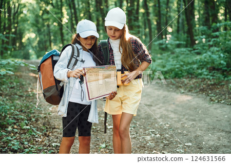 Using the map. Two girls is in the forest having a leisure activity, discovering new places Using the map. Two girls is in the forest having a leisure activity, discovering new places 124631566
