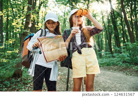 Using the map. Two girls is in the forest having a leisure activity, discovering new places Using the map. Two girls is in the forest having a leisure activity, discovering new places 124631567