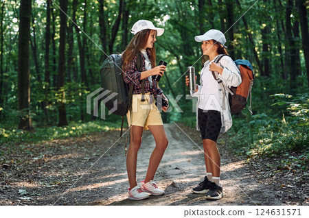Standing on the footpath. Two girls is in the forest having a leisure activity, discovering new places 124631571