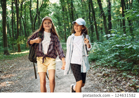 Walking forward. Two girls is in the forest having a leisure activity, discovering new places Walking forward. Two girls is in the forest having a leisure activity, discovering new places 124631582