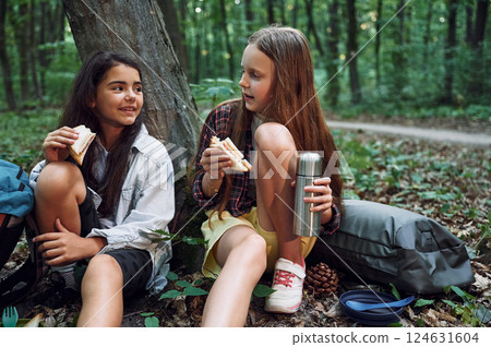 Taking a break, eating and drinking. Two girls is in the forest having a leisure activity, discovering new places Taking a break, eating and drinking. Two girls is in the forest having a leisure activity, discovering new places 124631604
