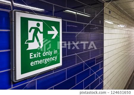 Emergency Exit Sign on Blue Tiled Wall in London Underground Station 124631650