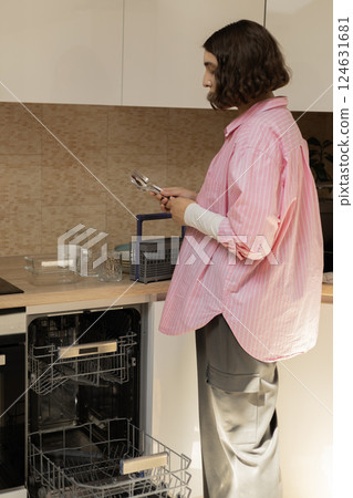 Young woman holding clean cutlery in her hand in the kitchen 124631681