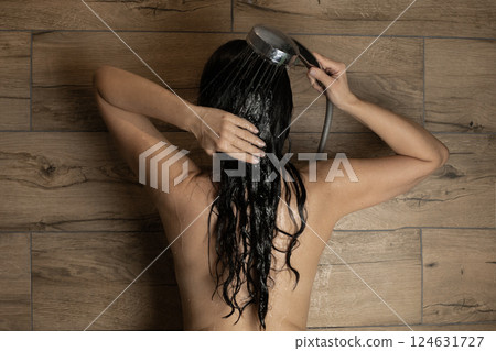 young woman washing dark curly hair in the shower, spa and beauty concept 124631727