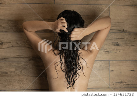 young woman in bathroom massaging long dark curly hair in shower, spa and beauty concept young woman in bathroom massaging long dark curly hair in shower, spa and beauty concept 124631728