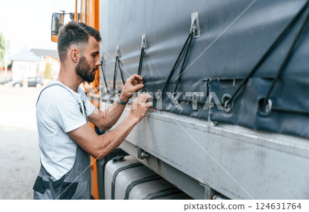 Checking the ropes. Man in unifrom doing service for big truck vehicle 124631764