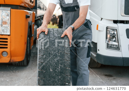 Moving broken tire. Man in unifrom doing service for big truck vehicle 124631770