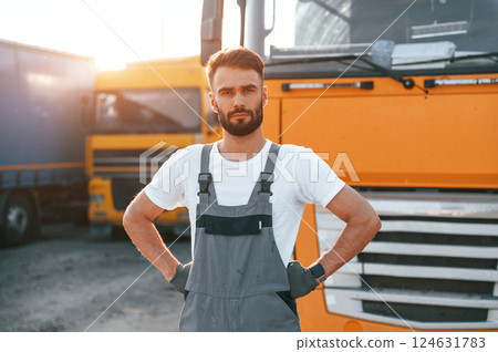Standing and posing for the camera. Man in unifrom doing service for big truck vehicle Standing and posing for the camera. Man in unifrom doing service for big truck vehicle 124631783