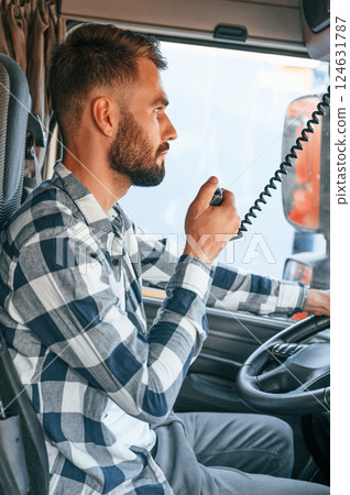 Using radio. Young truck driver is with his vehicle at daytime 124631787