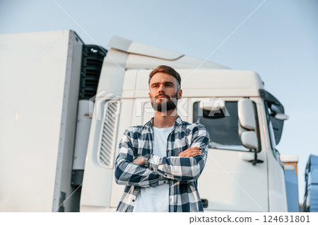 With arms crossed. Young truck driver is with his vehicle at daytime 124631801