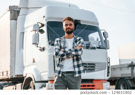 With arms crossed. Young truck driver is with his vehicle at daytime 124631802