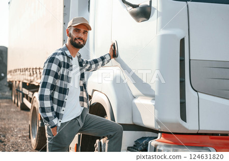 Standing by the door. Young truck driver is with his vehicle at daytime Standing by the door. Young truck driver is with his vehicle at daytime 124631820