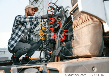 Checking the wires connection. Young truck driver is with his vehicle at daytime 124631829
