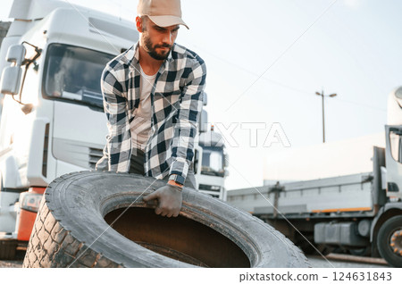 With broken tire. Young truck driver is with his vehicle at daytime With broken tire. Young truck driver is with his vehicle at daytime 124631843