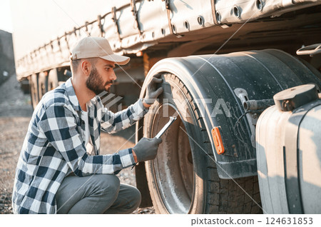 Testing the tires. Young truck driver is with his vehicle at daytime 124631853