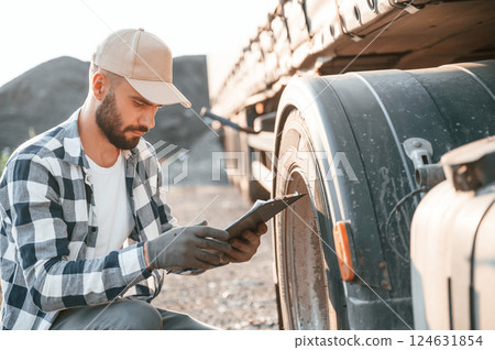 Testing the tires. Young truck driver is with his vehicle at daytime 124631854