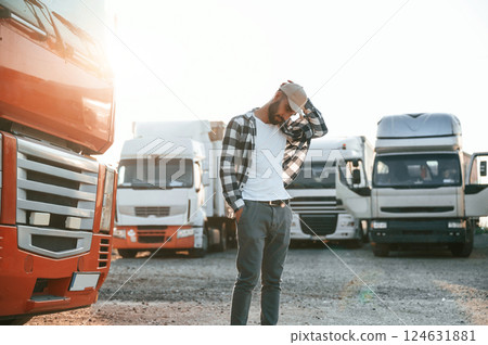Standing and feeling bored. Young truck driver is with his vehicle at daytime 124631881
