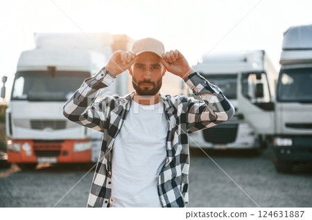 Front view. In cap. Young truck driver is with his vehicle at daytime 124631887