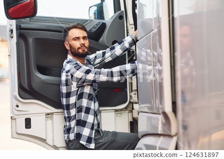 Opening the door. Young truck driver is with his vehicle at daytime 124631897