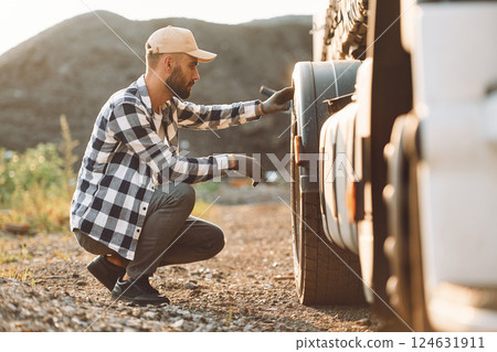 Working with damaged tire. Young truck driver is with his vehicle at daytime 124631911