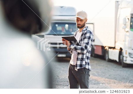 With black notepad. Young truck driver is with his vehicle at daytime 124631923