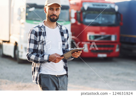 With black notepad. Young truck driver is with his vehicle at daytime 124631924