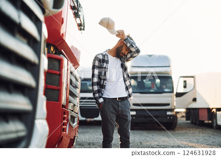 Tired, walking outside. Young truck driver is with his vehicle at daytime Tired, walking outside. Young truck driver is with his vehicle at daytime 124631928