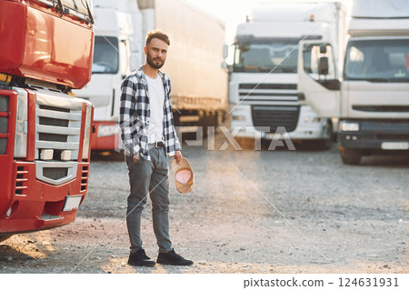 Tired, walking outside. Young truck driver is with his vehicle at daytime Tired, walking outside. Young truck driver is with his vehicle at daytime 124631931