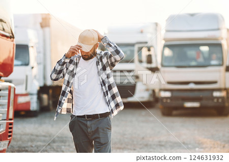 Wearing the cap. Young truck driver is with his vehicle at daytime Wearing the cap. Young truck driver is with his vehicle at daytime 124631932