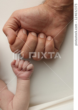 Two hands: man and child. Father and son touching fists. Dad and newborn son boys holding hands together. Little and big fists of father and son.  124632373