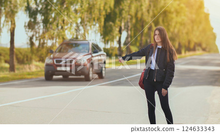 A young girl stands on the road and tries to stop any car. A young girl stands on the road and tries to stop any car. 124633343