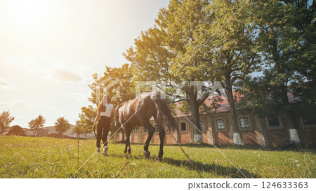 The girl walks with her beloved horse on a summer day. 124633363