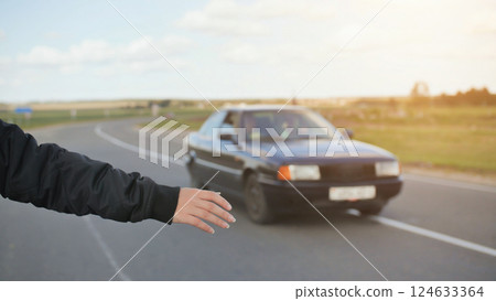 A young girl stands on the road and tries to stop any car. 124633364