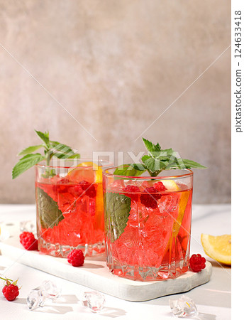 Cold homemade lemonade cocktail, mojito with mint, raspberry and fruits on a sunny table, refreshing summer drink recipe, detox diet and weight loss concept, restaurant menu 124633418