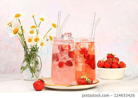 Strawberry iced tea or mint lemon cocktail, refreshing summer drink recipe. Glasses with berry lemonade on a light concrete table, detox diet and weight loss concept, restaurant menu. Strawberry iced tea or mint lemon cocktail, refreshing summer drink recipe. Glasses with berry lemonade on a light concrete table, detox diet and weight loss concept, restaurant menu. 124633426