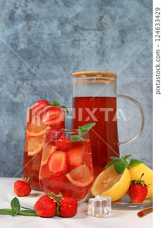 Strawberry iced tea or mint lemon cocktail, refreshing summer drink recipe. Glasses with berry lemonade on a light concrete table, detox diet and weight loss concept, restaurant menu. Strawberry iced tea or mint lemon cocktail, refreshing summer drink recipe. Glasses with berry lemonade on a light concrete table, detox diet and weight loss concept, restaurant menu. 124633429